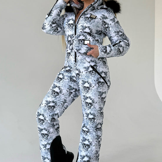 Women’s one piece ski suit by KRUTYAKOV with black and white skull print, fitted silhouette, and detachable fur hood