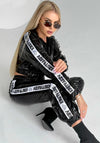 Women’s KAYRO glossy black tracksuit by KRUTYAKOV with cropped jacket, high-waisted joggers, and luxury streetwear shine