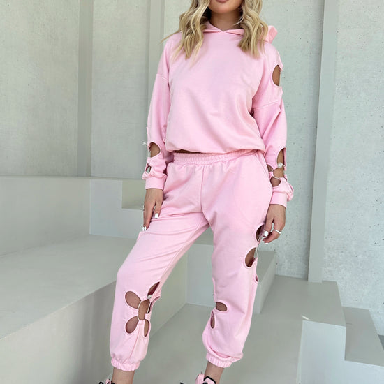 Feminine pink sweat suit set for women with hoodie, matching pants, and subtle designer floral cut-out accent