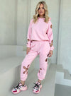 Feminine pink sweat suit set for women with hoodie, matching pants, and subtle designer floral cut-out accent