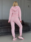 Women’s pastel pink two-piece tracksuit by KRUTYAKOV with zip hoodie, matching joggers, and relaxed fit