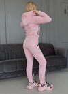 Pink women’s tracksuit by KRUTYAKOV styled as a cozy travel outfit, airport look, and casual city wear