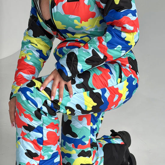 Women’s designer ski overall with bold multicolor print, premium zippers, and luxury resort outfit style