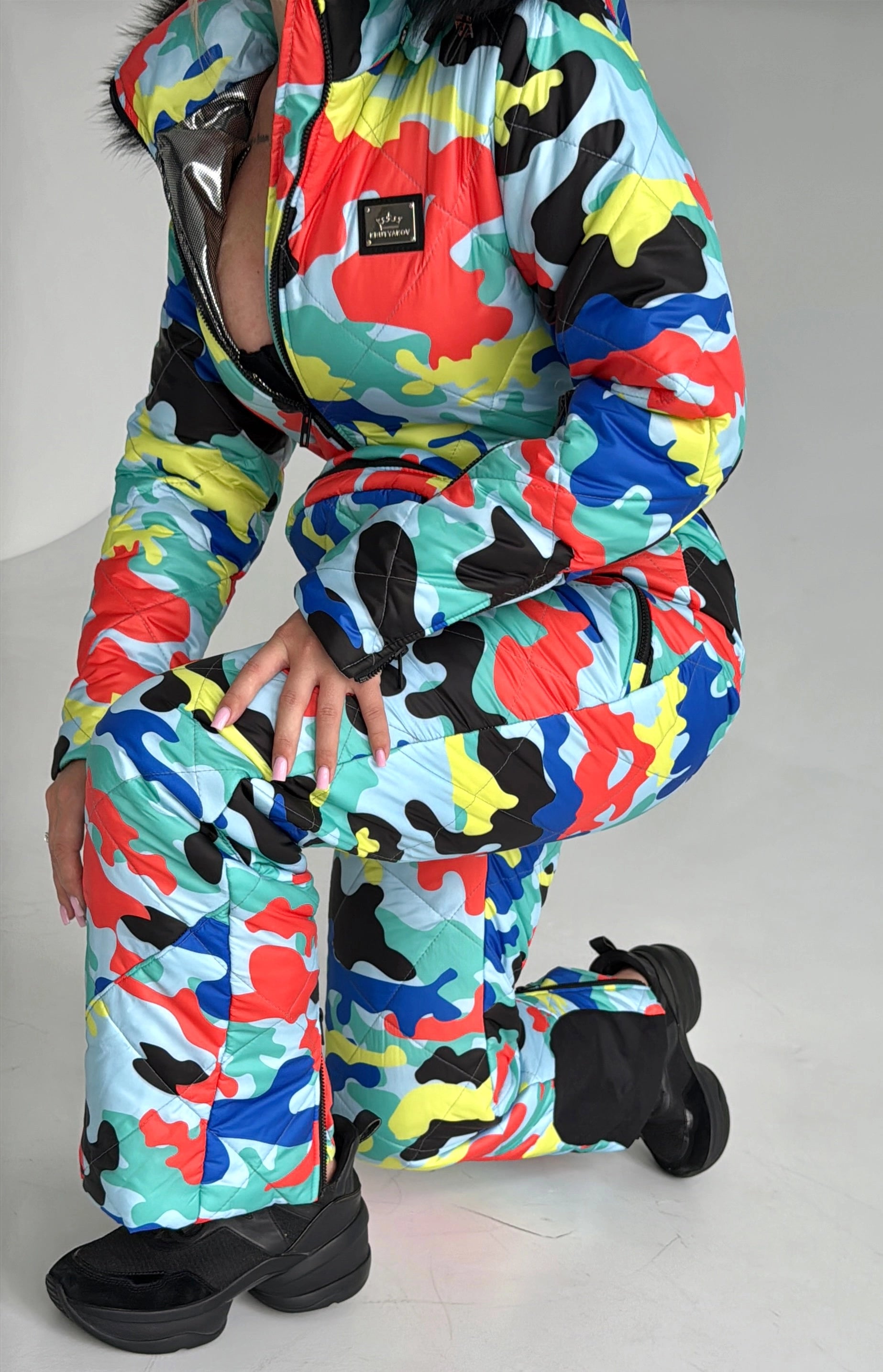 Women’s designer ski overall with bold multicolor print, premium zippers, and luxury resort outfit style