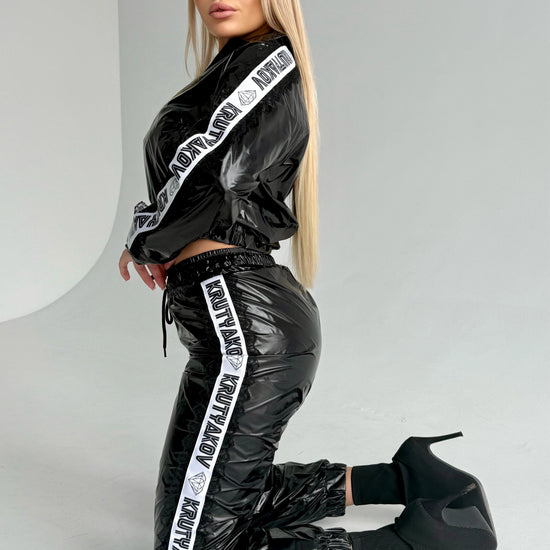 Black shiny women’s tracksuit set with cropped zip jacket and matching jogger pants by KRUTYAKOV