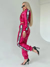 Fuchsia shiny women’s tracksuit set with cropped zip jacket, branded side stripes, and matching jogger pants