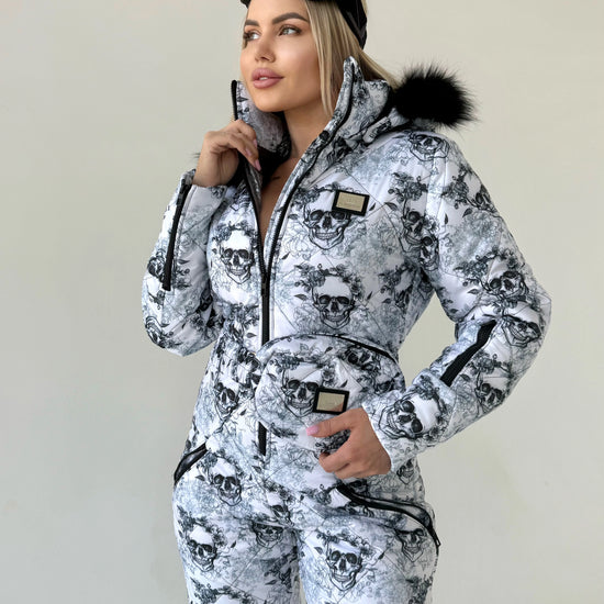 Lifestyle photo of women’s one piece snow suit with black white skull design for après-ski and resort outfits