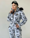 Lifestyle photo of women’s one piece snow suit with black white skull design for après-ski and resort outfits