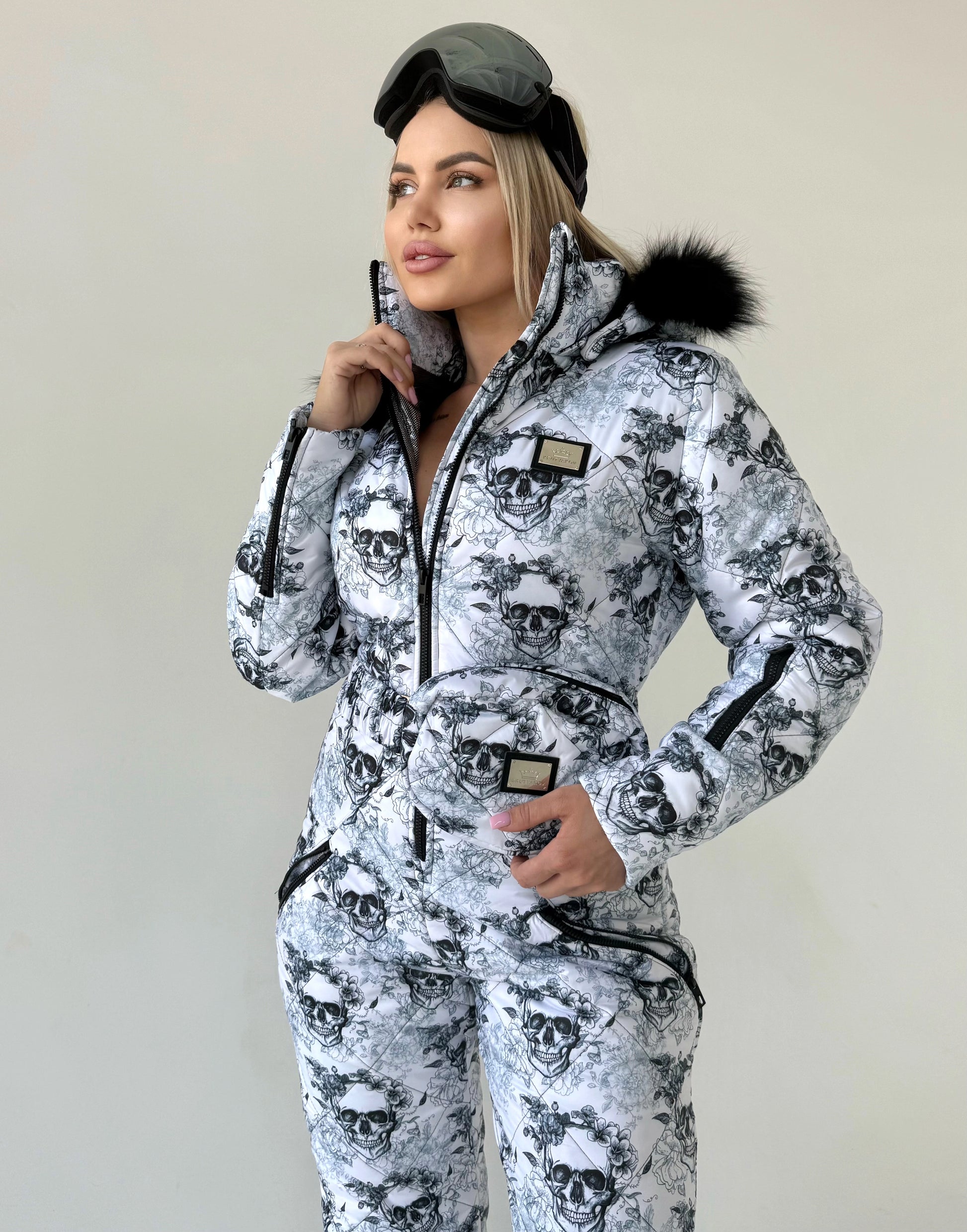 Lifestyle photo of women’s one piece snow suit with black white skull design for après-ski and resort outfits