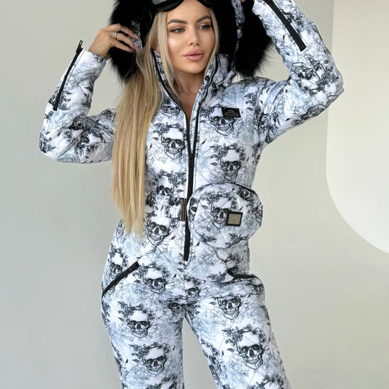 Full-body view of women’s black white skull ski suit with belt bag, hood, and winter-ready one-piece design