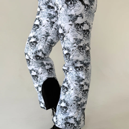 Women’s black white skull snowsuit styled for ski resorts, snowboarding trips, and winter mountain vacations