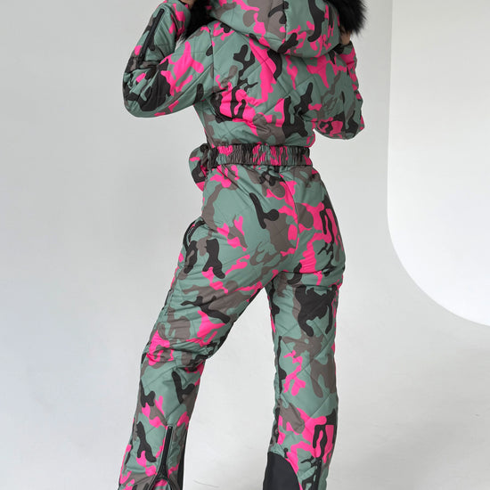 Full-body view of VALE pink camouflage snowsuit with fitted silhouette, insulated construction, and belt bag