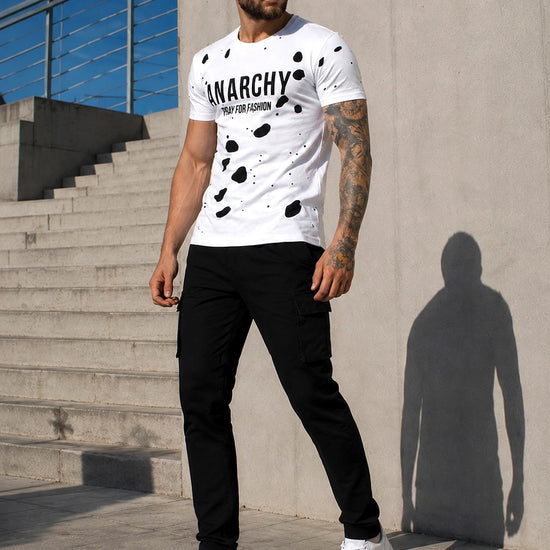 Male model wearing a white ANARCHY graphic T-shirt with black pants and white sneakers
