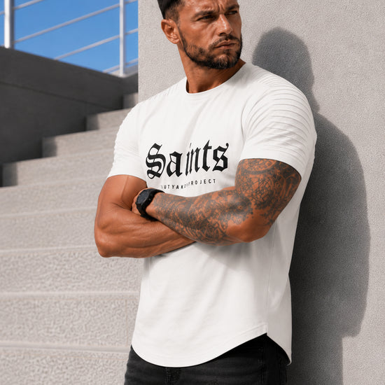 Male model wearing an off white SAINTS graphic T-shirt with black jeans in an urban casual outfit