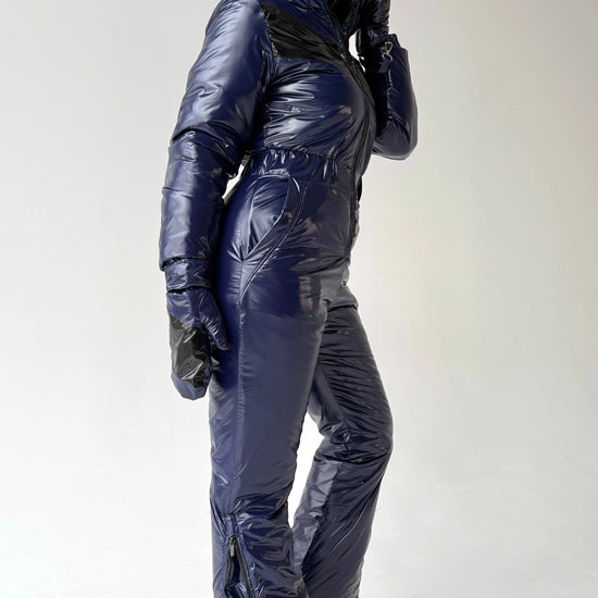 Side view of dark blue insulated ski overall for women with modern glossy finish and sporty luxury look