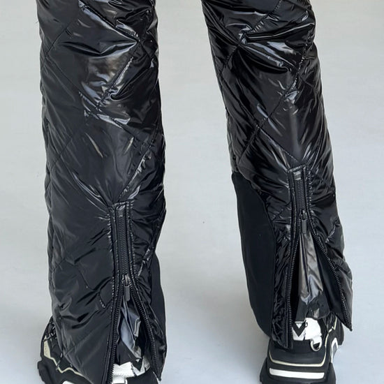 Rear ankle zippers on women’s black ski suit for easier fit over ski boots