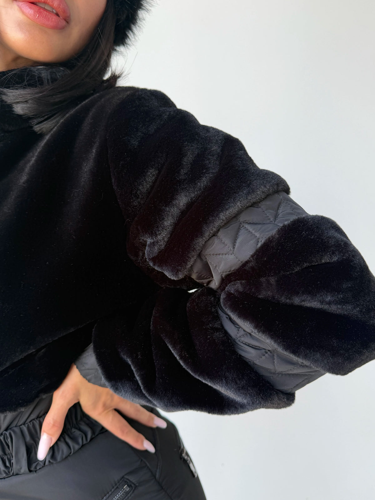 Black winter jumpsuit detail with eco fur texture and front zipper