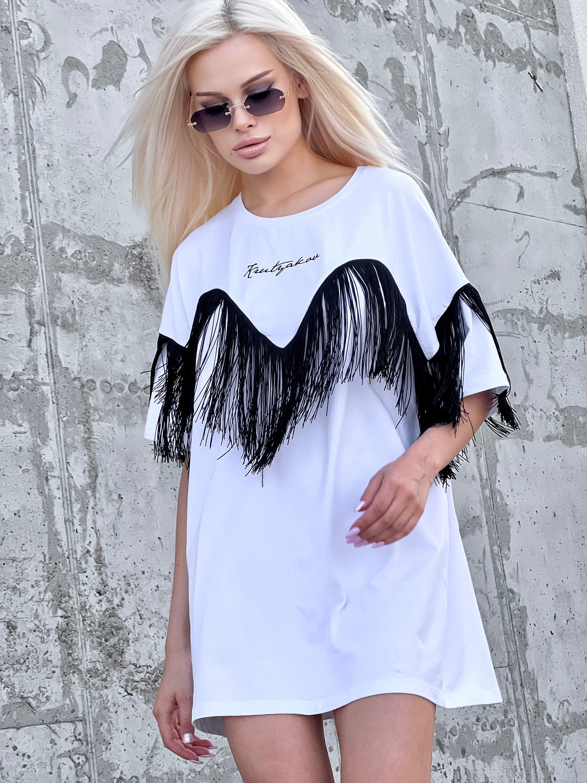 Side view of KRUTYAKOV oversized white T-shirt showing long fringe detail and loose comfortable shape
