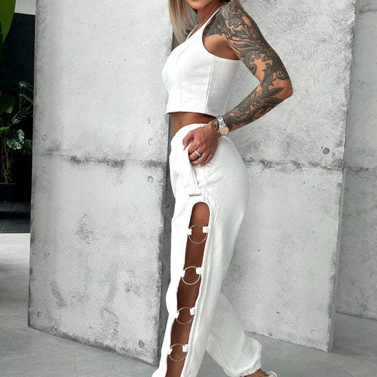 Women’s white joggers with bold cut-out leg design and metal ring accents