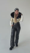 Side view of black and gold women’s ski jumpsuit with detachable fur hood and warm insulated winter fabric