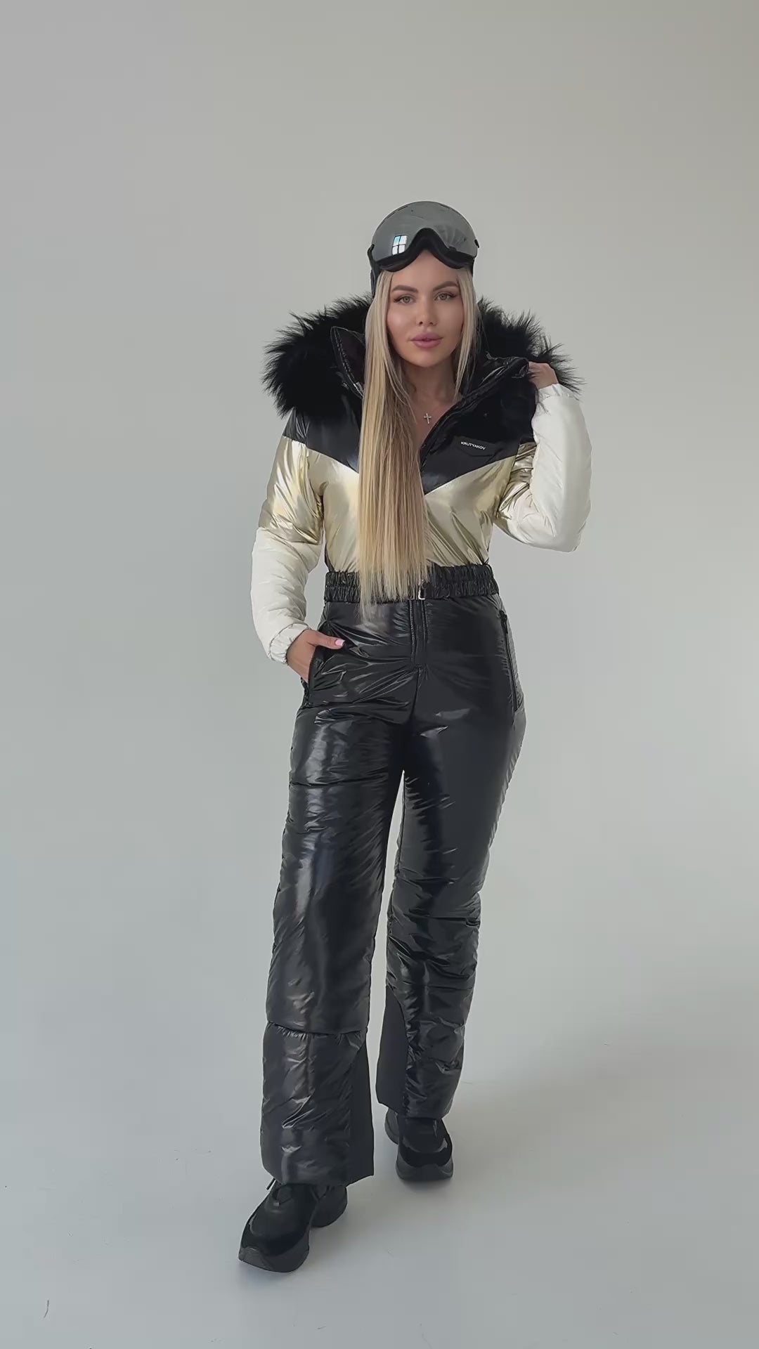 Side view of black and gold women’s ski jumpsuit with detachable fur hood and warm insulated winter fabric