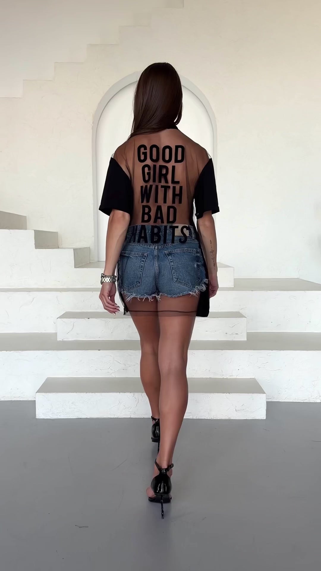 Back view of KRUTYAKOV black T-shirt showing sheer mesh panel and statement graphic print