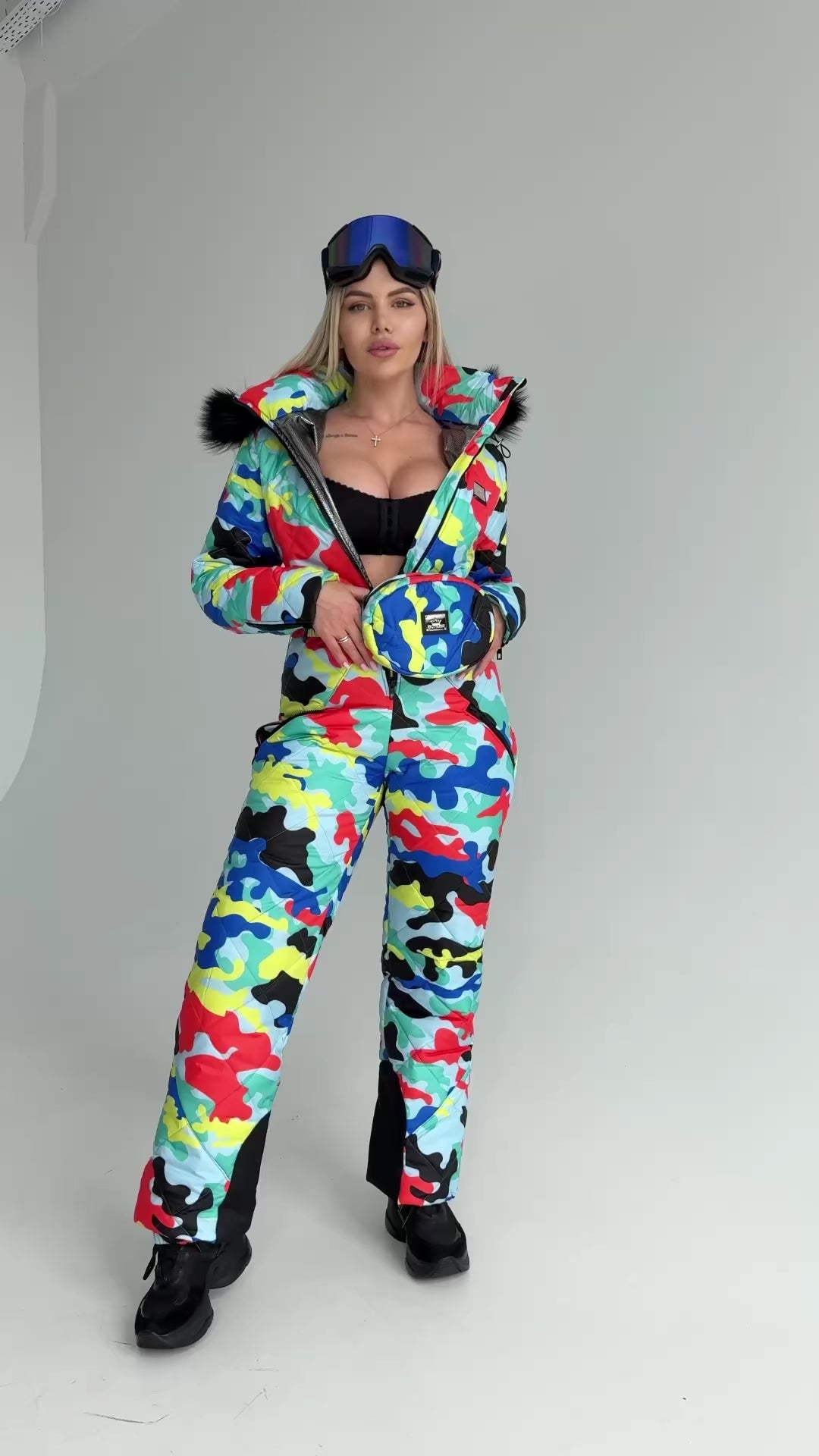 Side view of multicolored ski jumpsuit with removable fur hood, waist-shaping fit, and insulated winter fabric
