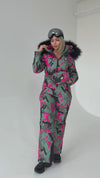 Side view of luxury après ski snowsuit with pink camo print, detachable faux fur hood, and zip pockets