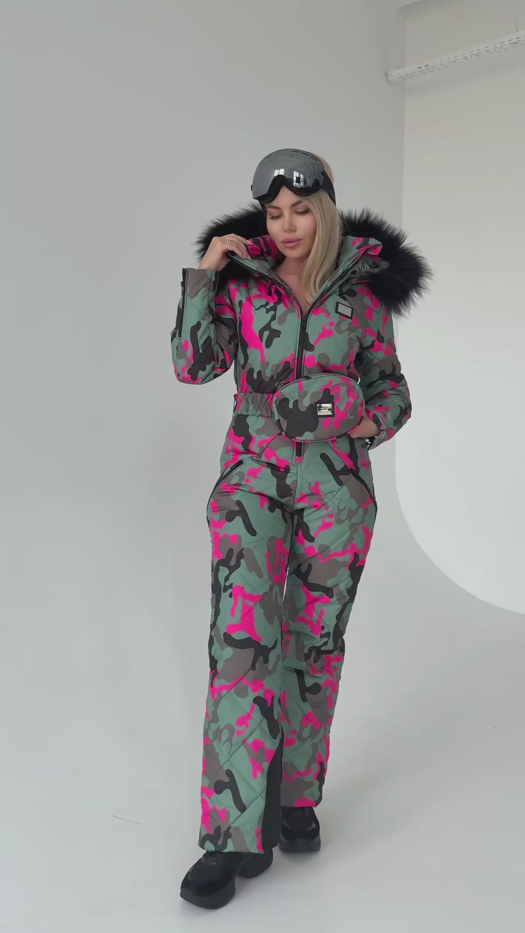 Side view of luxury après ski snowsuit with pink camo print, detachable faux fur hood, and zip pockets